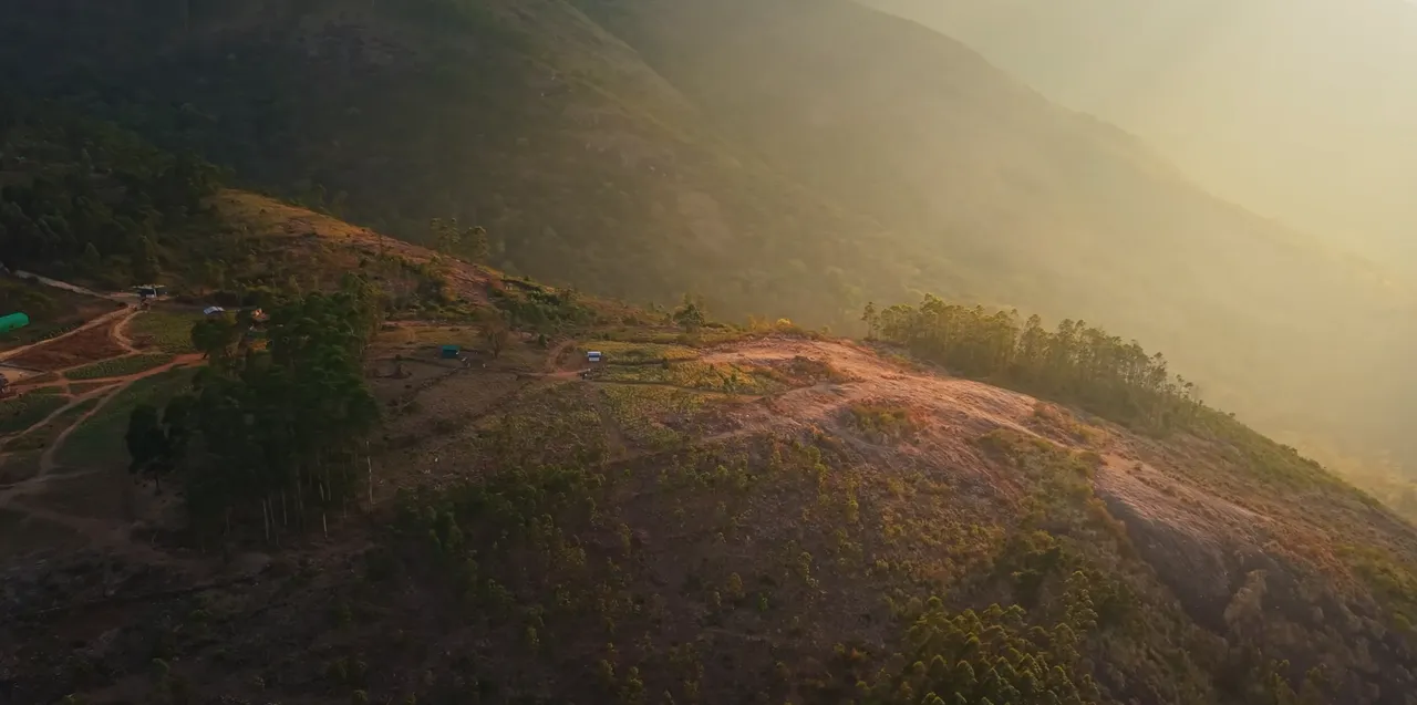 Golden evening light spreading across a cultivated mountain slope